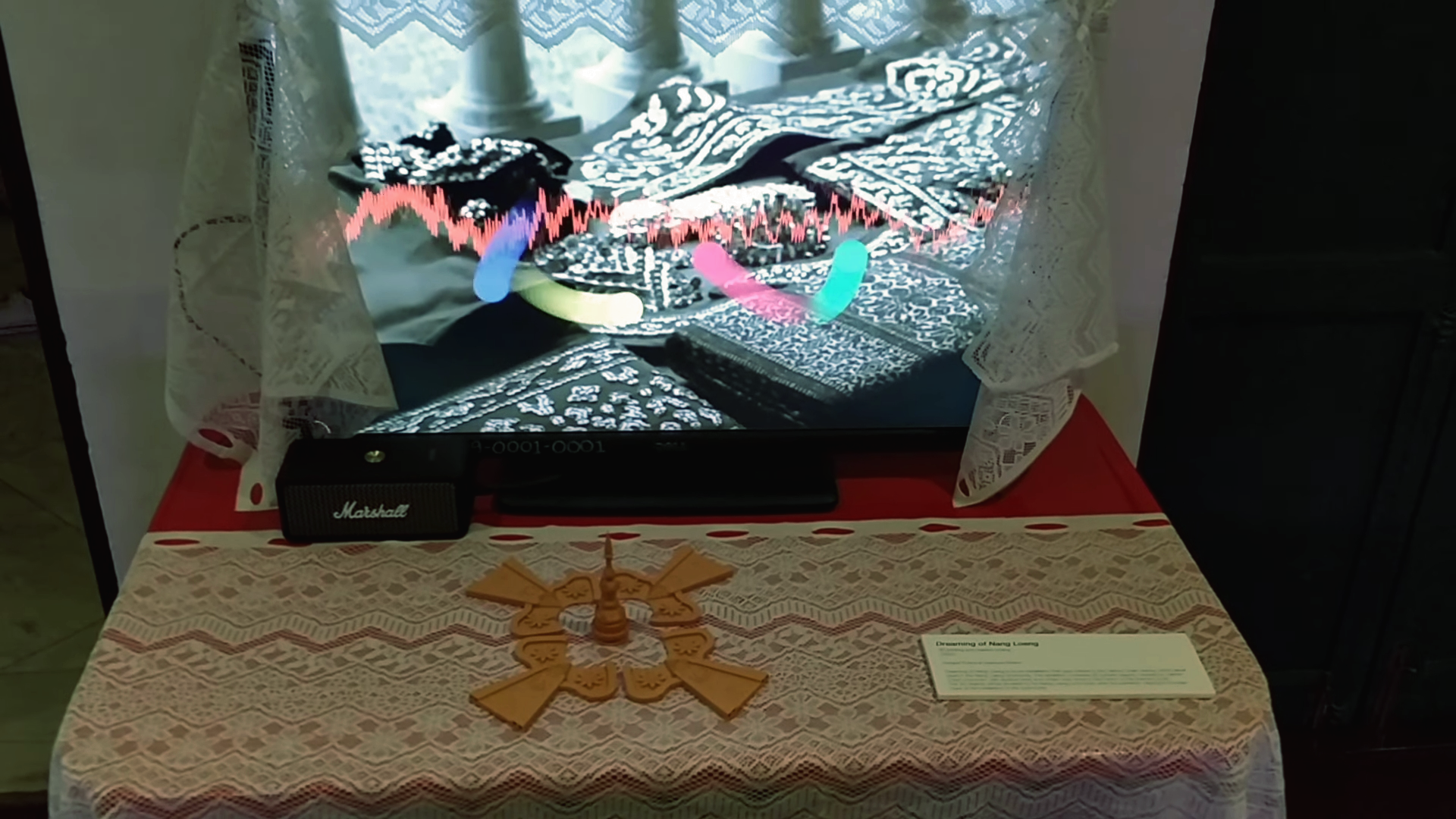 monitor with a digital effect, adorned by a small curtain on a table with five 3D printed pieces in front